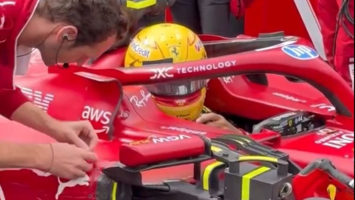 Hamilton pede ajuda para colocar fita na lateral de sua Ferrari