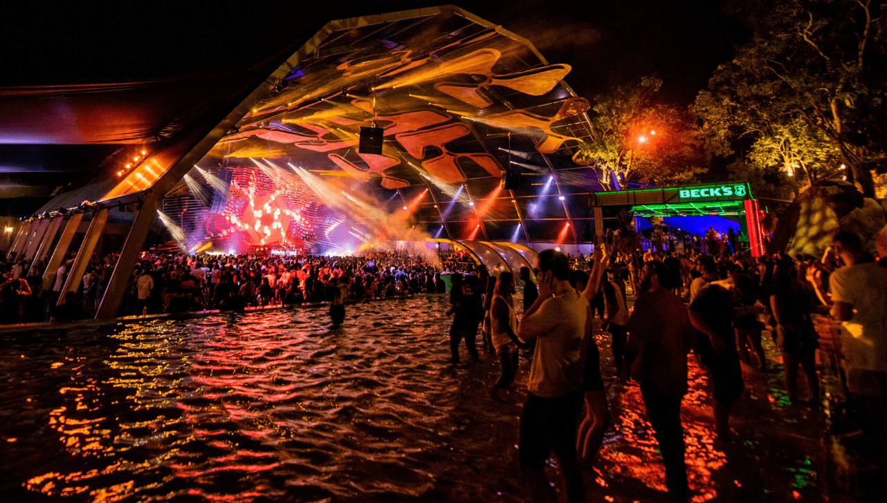 Palco principal do Ame Laroc Festival à noite, com luzes coloridas e multidão (Foto/Escape Magazine)