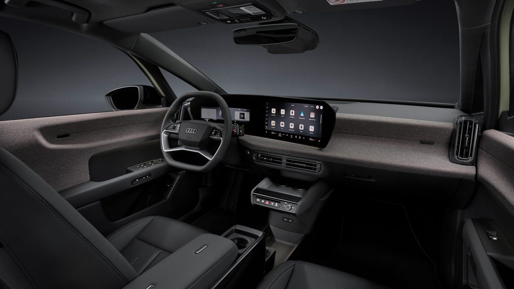 Studio static photo, interior, cockpit from the passenger side, multifunction steering wheel, MMI panoramic display, MMI touch display, fabric-covered surface softwrap, centre armrest with modular Fidlock fastening system and phone tray with inductive charging capability