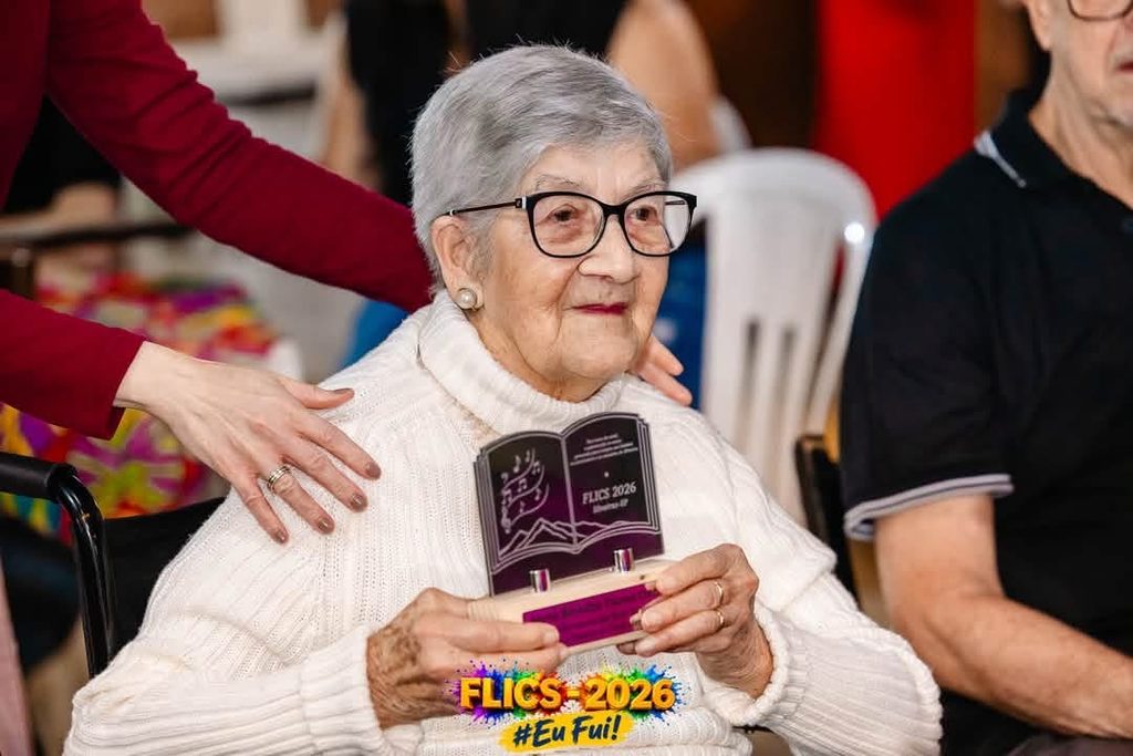 Dona Maria Cintra, homenageada pelo Coral do Menino Jesus, que fundou em 1985, durante FLICS 2026 em Silveiras. Foto: Prefeitura de Silveiras.
